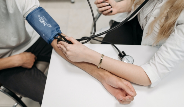 Photo of a medical professional using a blood pressure cuff on a patient's left arm.