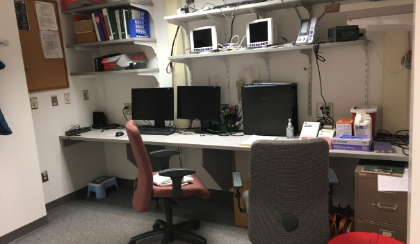 Photo of a long desk along a wall with two empty office chairs in front of a dual-monitor workstation.